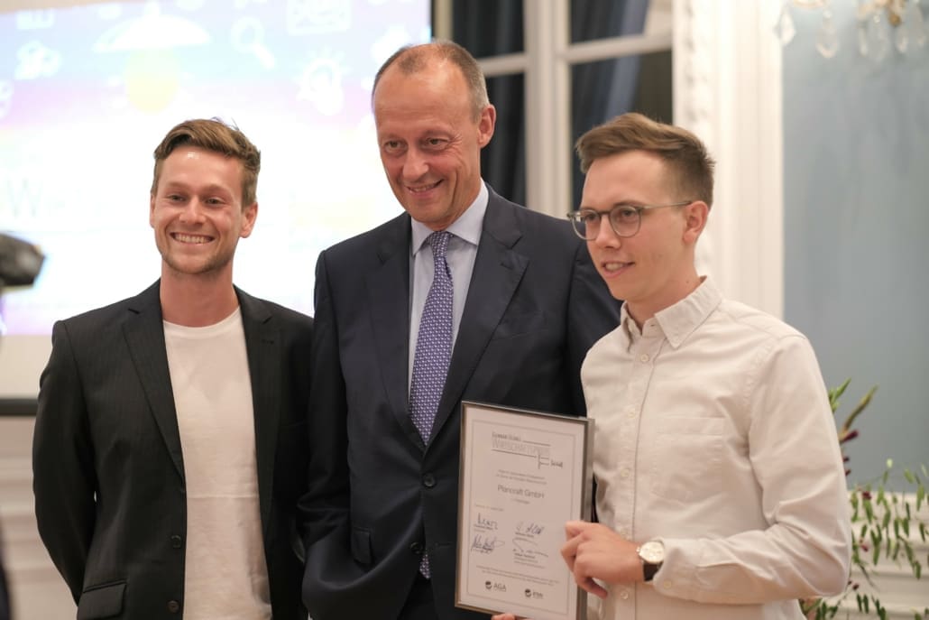 Friedrich Merz mit den Gewinnern Julian Wiedenhaus (l.) und Till Zimmermann (r.) von Plancraft. 